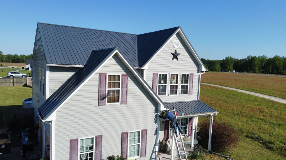 A metal roofing contractor working on a house’s roof